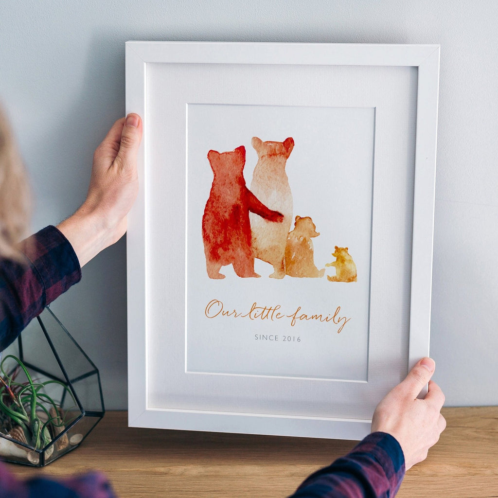 A custom bear family print in a white frame: The watercolour style illustrated family of bears show two parent bears, a child, and a baby bear. Underneath the customised words say 'Our little family - since 2016.'