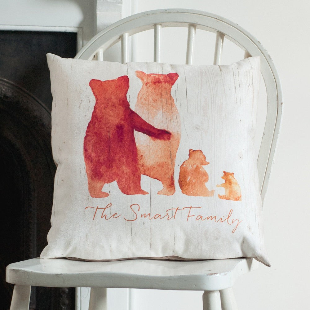 A cushion sits upon a chair, near a fireplace. On the cushion is a family of orange bears, with two parents, a baby and a toddler bear. Beneath the bears are the words 'The Smart Family'