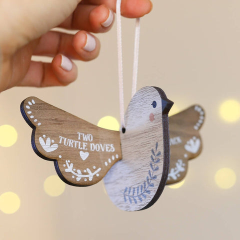 A wooden turtle dove Christmas decoration. One wing states 'two turtle doves' with pretty details around the edges. 