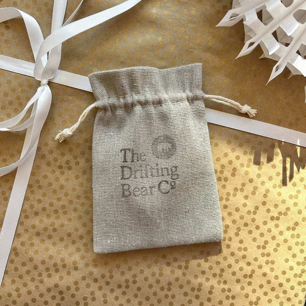Drawstring bag with 'The Drifting Bear Co.' branding on a gold polka dot gift wrapped background.