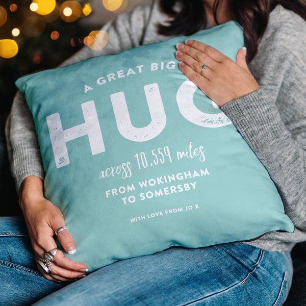 This image features a personalised cushion in blue. The words on the cushion say 'A great big hug across 10599 miles from Wokingham to Somersby, with love from Jo x'.
