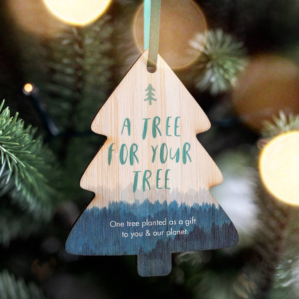 A Christmas Tree shaped decoration with the words 'a tree for your tree' in large text, followed with 'one tree planted as a gift to you & our planet' in smaller text underneath. Printed on bamboo, cut in to a classic Christmas tree shape.