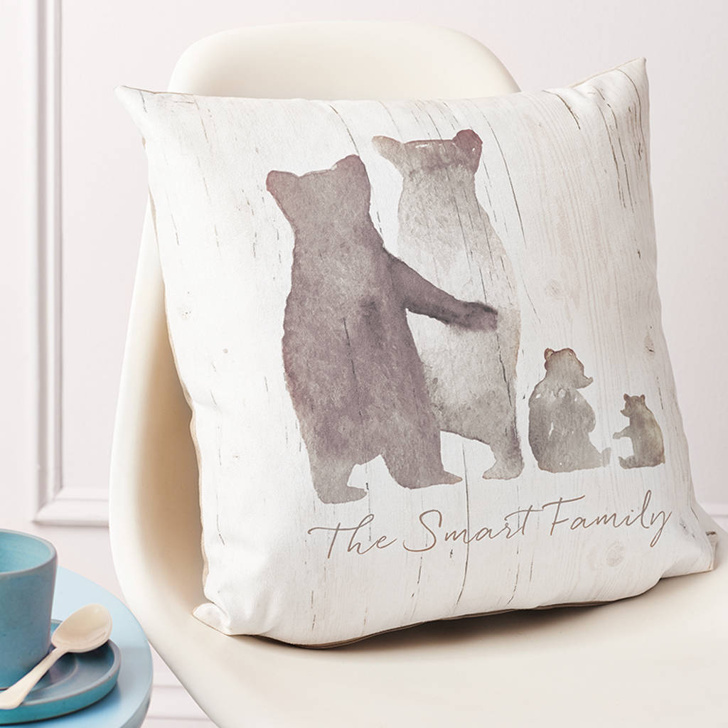 A large, plump cushion sits upon a chair. On the cushion is a family of grey bears, with two parents and 2 young children. Beneath the bears is the text 'The Smart Family'