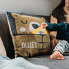 A cushion with a bear design with a pocket on the front designed to hold a bedtime story book. The cushion has been personalised with the word "Ollie's bedtime story cushion' on the front.