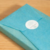 This image shows a pristinely wrapped oak photo block in teal tissue paper, with a circular label with the words 'made especially for you by the Drifting Bear Co' written on it.