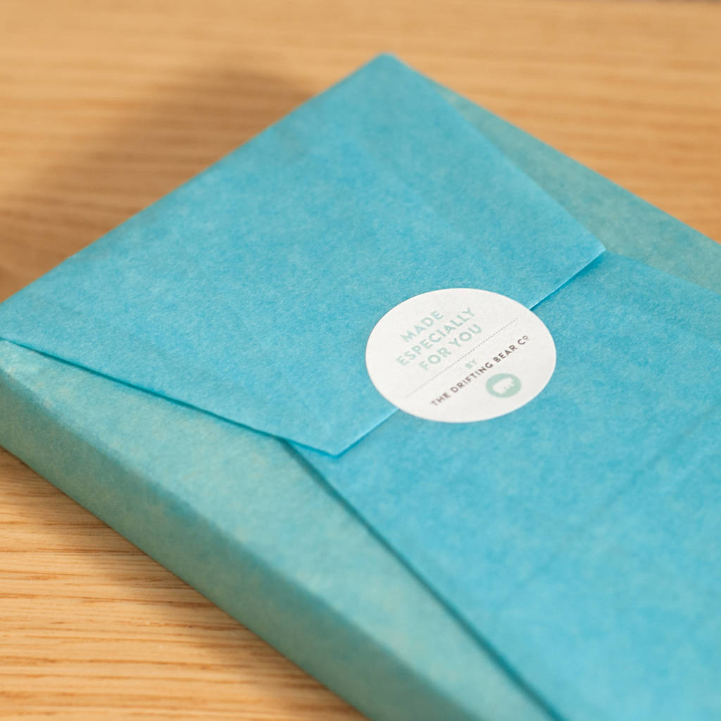 This image shows a pristinely wrapped oak photo block in teal tissue paper, with a circular label with the words 'made especially for you by the Drifting Bear Co' written on it.