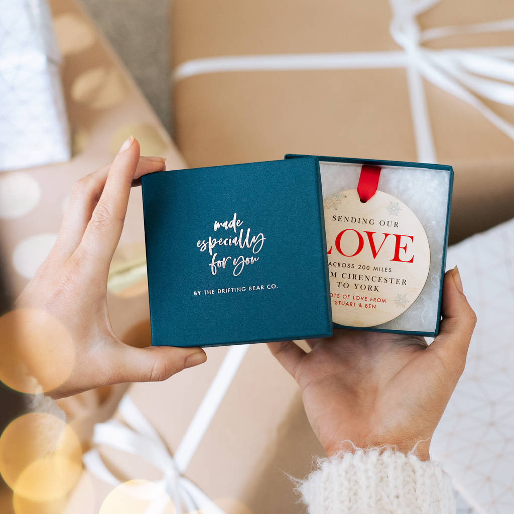 A personalised Christmas bauble with the distance the love has travelled written on it. It is in a gift box with the words 'made especially for you' on the front.