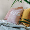 This image shows three throw cushions, the central cushion is a soft blush pink with the words 'a great big hug across 11170 miles from Dunoon to Papamoa, with love from Carolyn and Dave' on it.